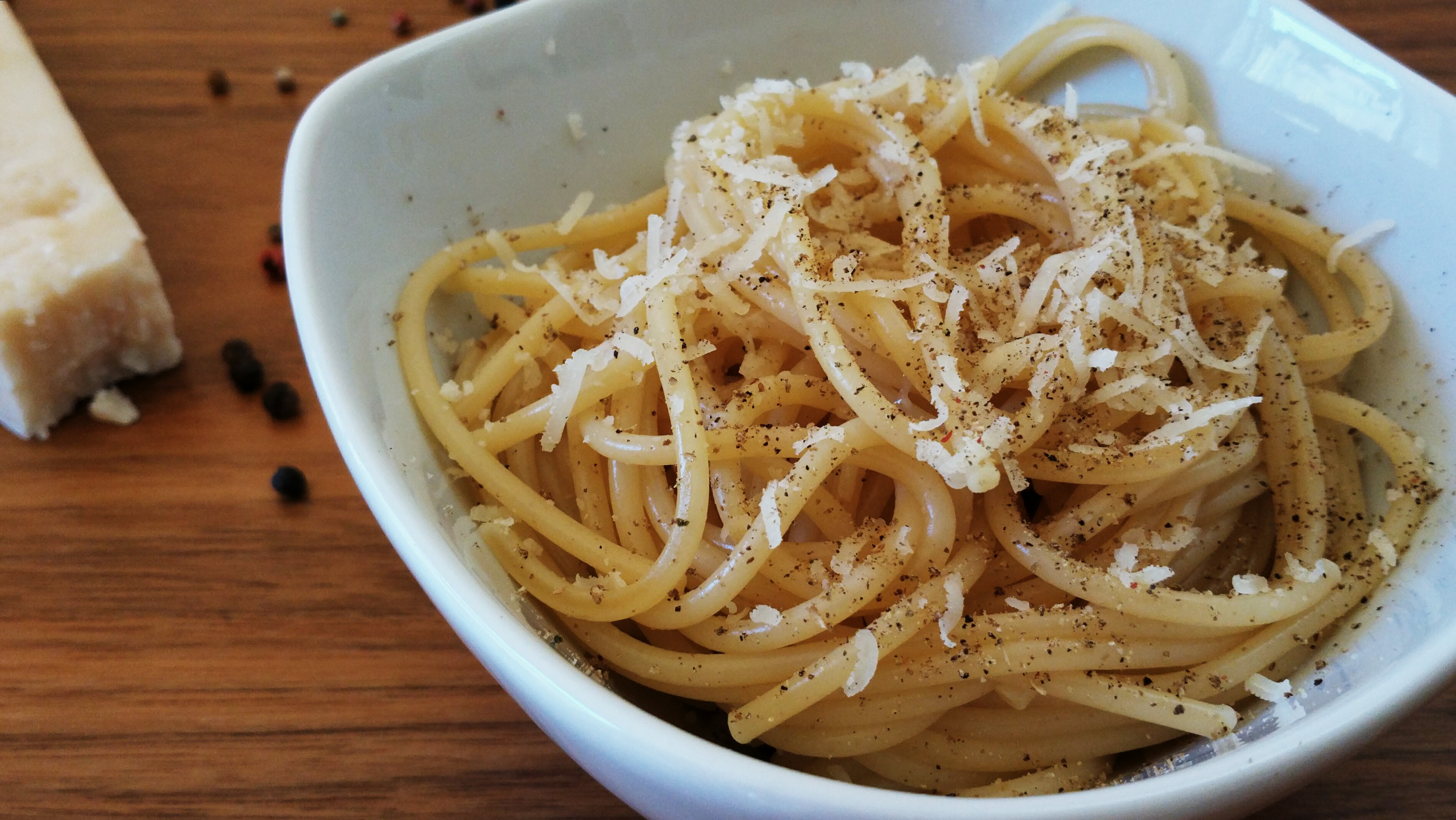 A twirl of cacio e pepe, glossy cheese sauce, coarse black pepper, Natural window light, ivory linen, handmade ceramic, shallow depth of field, no text, no logo, no watermark, fine-dining magazine photograph. Cacio e Pepe