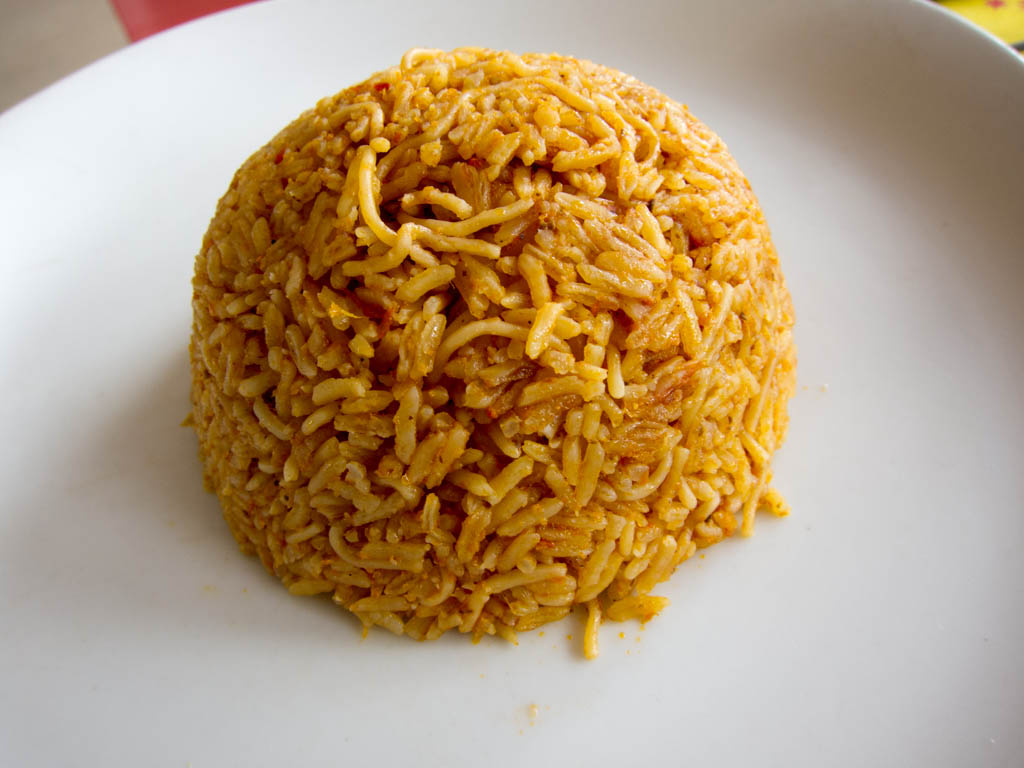 Photoreal photograph of the finished dish Arroz de tomate (Arroz), the actual plate from Guinea-Bissau, handmade ceramic, natural window light, shallow depth of field, no text, no logo, no people, Natural window light, ivory linen, handmade ceramic, shallow depth of field, no text, no logo, no watermark, fine-dining magazine photograph. Arroz de tomate