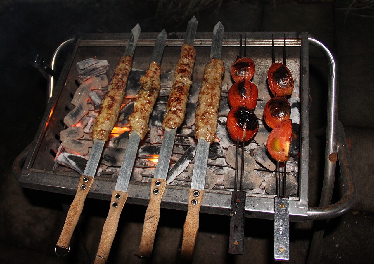 Photoreal photograph of the finished dish Kabab koobideh (کباب کوبیده), the actual plate from Iran, handmade ceramic, natural window light, shallow depth of field, no text, no logo, no people, Natural window light, ivory linen, handmade ceramic, shallow depth of field, no text, no logo, no watermark, fine-dining magazine photograph. Kabab koobideh