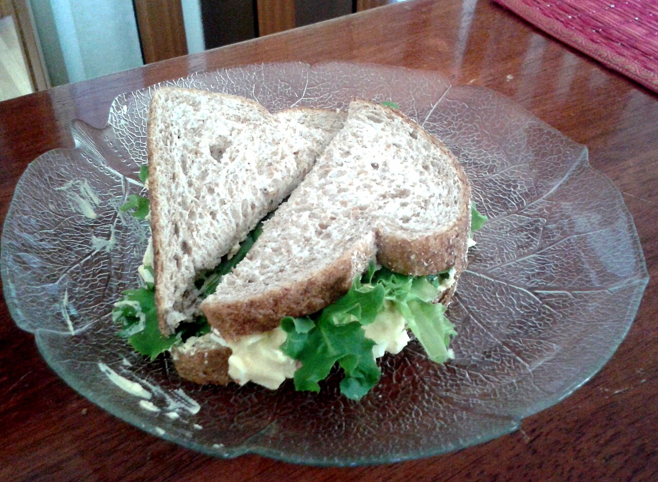 Photoreal photograph of the finished dish Egg salad sandwich (たまごサンド), the actual plate from Japan, handmade ceramic, natural window light, shallow depth of field, no text, no logo, no people, Natural window light, ivory linen, handmade ceramic, shallow depth of field, no text, no logo, no watermark, fine-dining magazine photograph. Egg salad sandwich