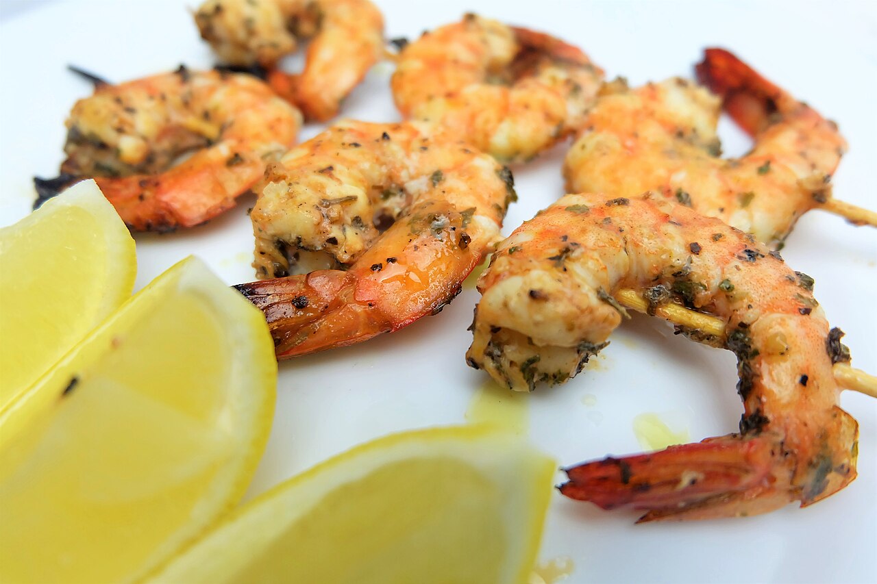 Photoreal photograph of the finished dish Grilled shrimp (Camarão), the actual plate from Mozambique, handmade ceramic, natural window light, shallow depth of field, no text, no logo, no people, Natural window light, ivory linen, handmade ceramic, shallow depth of field, no text, no logo, no watermark, fine-dining magazine photograph. Grilled shrimp