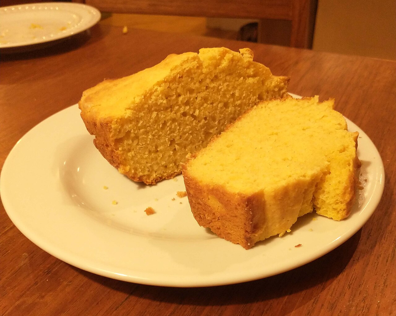 Photoreal photograph of the finished dish Cornbread (тукано леб), the actual plate from North Macedonia, handmade ceramic, natural window light, shallow depth of field, no text, no logo, no people, Natural window light, ivory linen, handmade ceramic, shallow depth of field, no text, no logo, no watermark, fine-dining magazine photograph. Cornbread