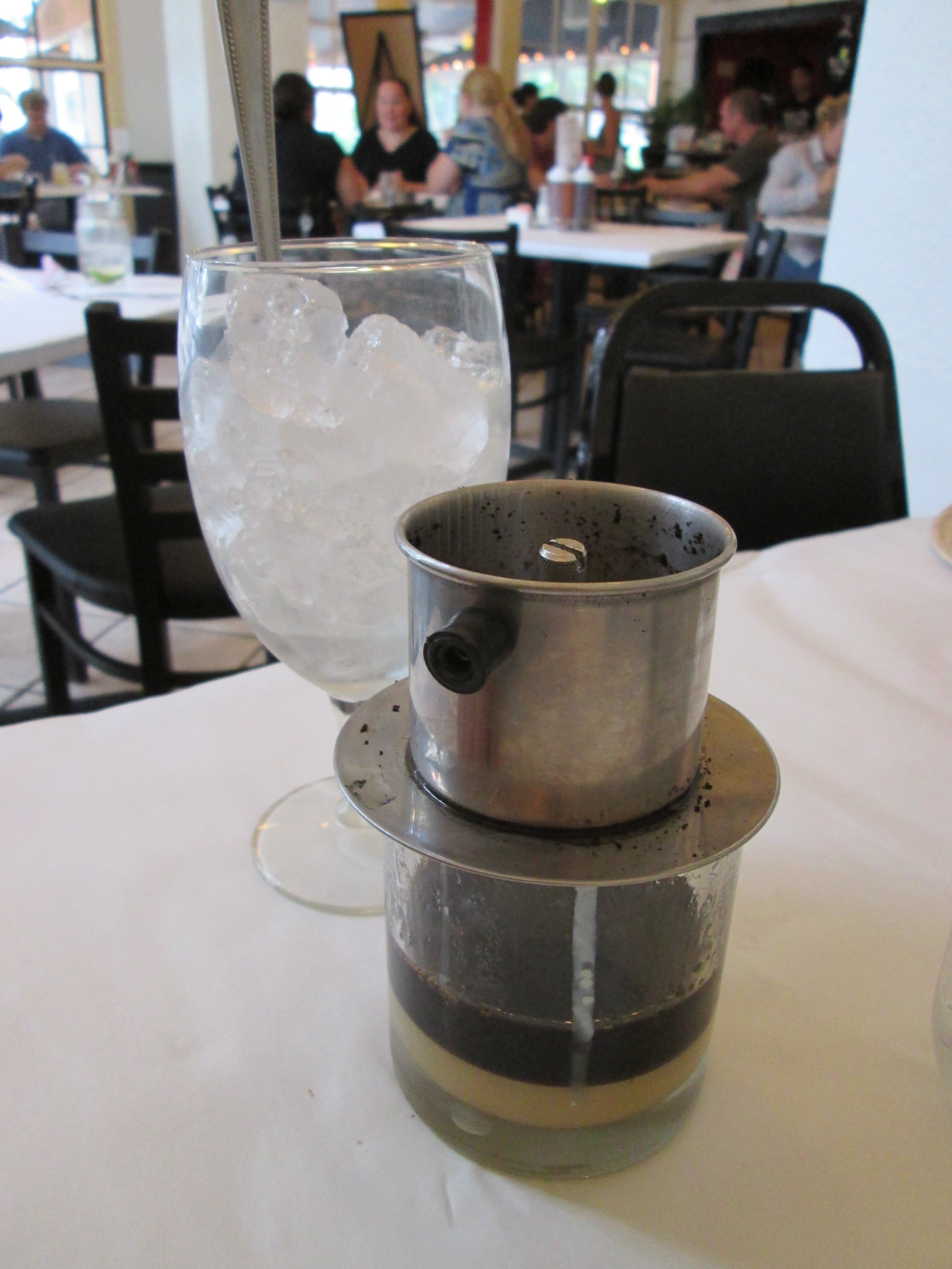 Two glasses of Vietnamese iced coffee, condensed milk swirling into dark coffee over ice, Natural window light, ivory linen, handmade ceramic, shallow depth of field, no text, no logo, no watermark, fine-dining magazine photograph. Vietnamese Iced Coffee